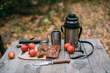Tourist lunch in the forest. Thermos with food on a wooden table.