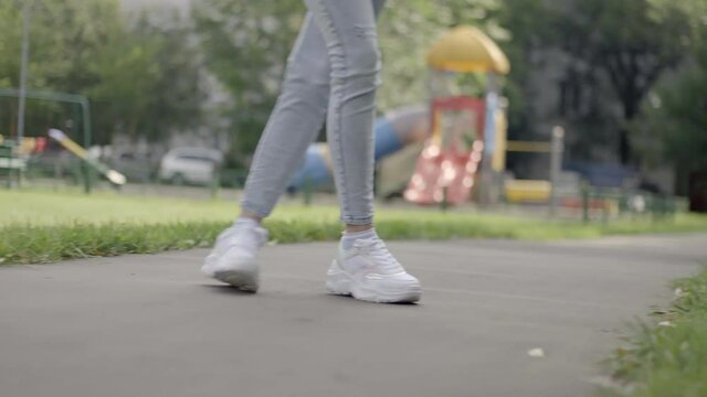 legs of a young girl in white sneakers are hitting a golf ball
