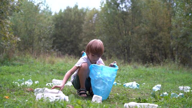 children remove plastic garbage and put it in a biodegradable garbage bag in the open air. The concept of ecology, waste processing and nature protection. Environmental protection