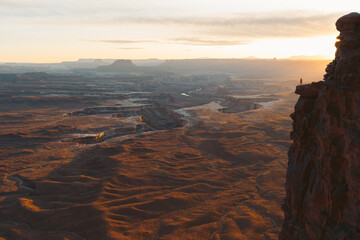 Woman Hiker standing on cliff in Canyonlands National Park at sunset 