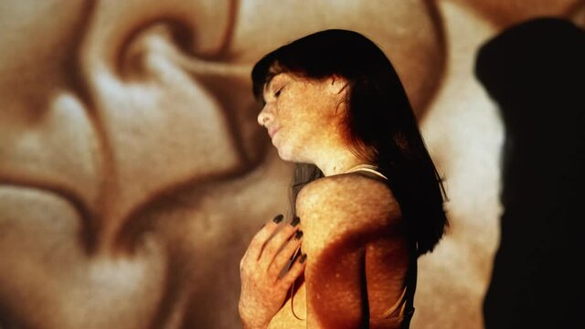 Seductive woman. Female sensuality. Inner fantasy. Love desire. Flirty dreamful lady stroking skin eyes shut in ecstasy on warm golden sand glitter flow motion projection.