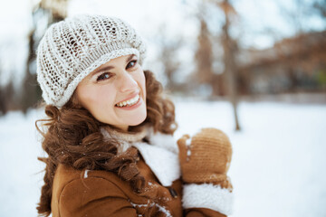 Portrait of happy stylish woman outside in city park in winter