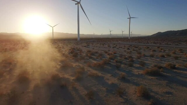 4k Aerial of wind turbines energy through dust cloud desert