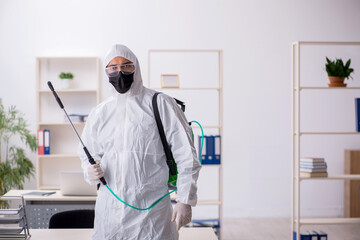 Fototapeta premium Young male contractor disinfecting office during pandemic