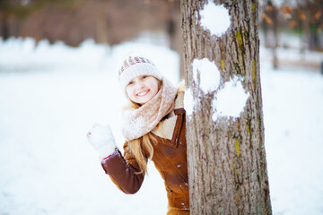 smiling girl playing snowball outdoors in city park in winter
