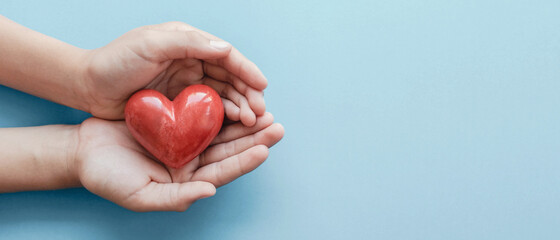 hands holding red heart on blue background, health care, love, organ donation, family insurance and CSR concept, world heart day, world health day