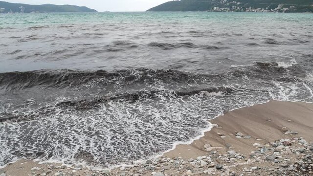 Black muddy waves of healing sea mud on a mud beach, or a black beach in Igalo, Montenegro. The beach in front of the spa building in Igalo