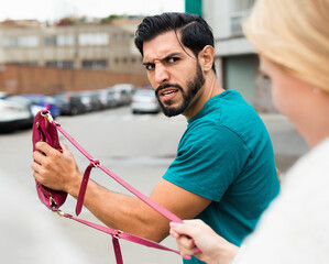 Woman is aggressive on male because he is taking her handbag outdoor.