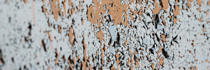 Peeling paint on the wall. Panorama of a concrete wall with old cracked flaking paint. Weathered rough painted surface with patterns of cracks and peeling. Wide panoramic grunge texture for background
