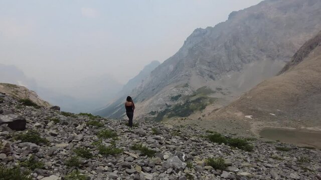 A young female hiker is posing in front of smoky mountains near Calgary, Alberta, Canada in Kananaskis Country. Rae  Glacier trail is located near Elbow Lake.  