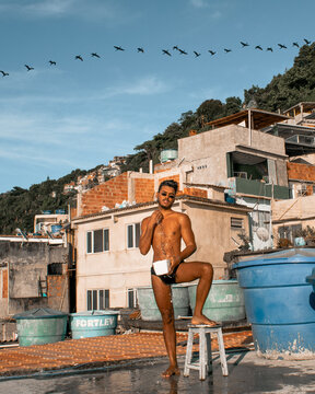 Man taking a bath in the favela with birds on the blue sky