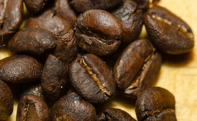 macro shot of a bunch of roasted coffee beans on a wooden table. 