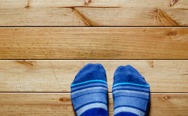 top view of mans feet with blue socks on a wooden floor.