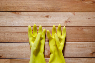 two yellow rubber wiping gloves on a wooden floor, texture wallpaper.