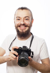 young bearded photographer taking pictures with digital camera over white background.