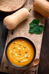 Butternut squash soup with pumpkin seeds and cream in a bowl on wooden, Table top view