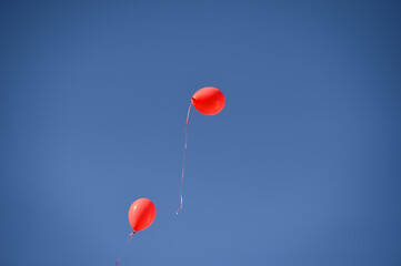 Fototapeta na wymiar Red balloons, symbol of World Duchenne Awareness Day, are released into the blue open sky.