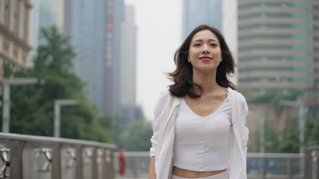4k slow motion of conficent pretty young asian woman walking in the urban city street with high building in the background at Chengdu China