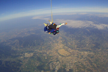 Fototapeta premium jump with an instructor in tandem in clear good weather , from below you can see the outlines of the historic center of Lucca , in summer