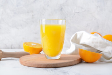 Glass with tasty orange juice on light background