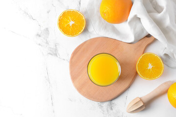 Glass with tasty orange juice on light background