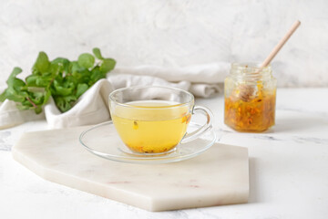 Cup of tasty tea with sea buckthorn on light background