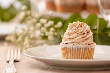 Plate with tasty wedding cupcake on table