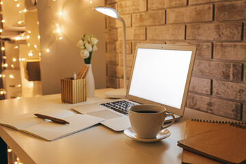 Stylish workplace with glowing lamp, glowing lights and modern laptop near brick wall