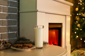 Table with glass of milk and cookies in living room decorated for Christmas