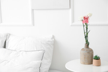 Vase with beautiful carnations on table in bedroom