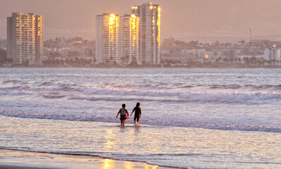 two children playing in the ocean at sunset in La Serena
