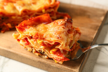 Delicious lasagna with tomato sauce on wooden board
