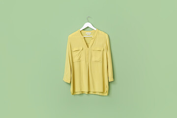 Hanger with stylish blouse on color background
