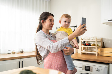Caucasian mother holding little baby and video call online with family