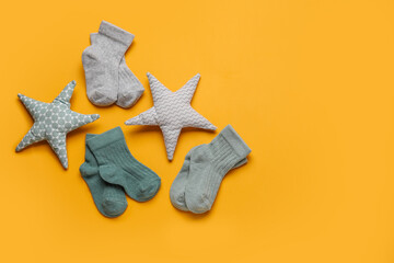 Baby socks and toys on color background