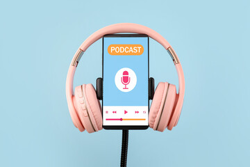 Modern headphones and mobile phone with podcast playlist on screen against color background