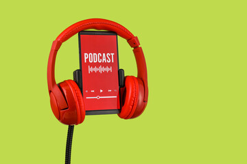 Modern headphones and mobile phone with podcast playlist on screen against color background