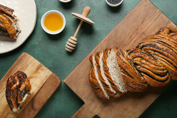 Wooden boards with sliced poppy seed bun and honey on color background