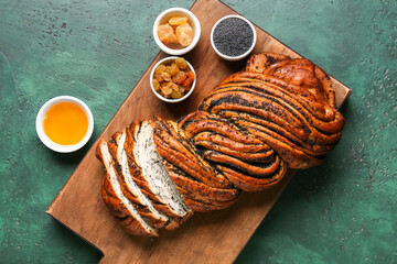 Wooden board with sliced poppy seed bun and ingredients on color background