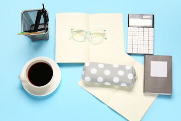 Stylish pencil case, eyeglasses, cup of coffee and stationery on color background