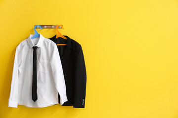 Hanger with stylish school uniform on color wall in room