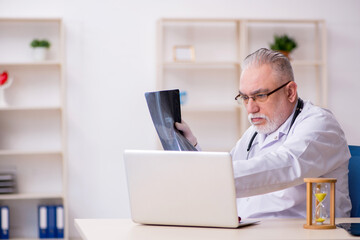 Old male doctor in time management concept