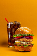 Fresh Big chicken burger with double cutlet and cola on orange background. Fat unhealthy street...