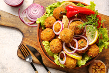 Bowl with tasty cod cutlets on light background, closeup