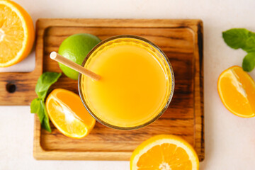 Board with glass of tasty orange juice on light background, closeup