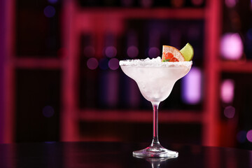 Glass of tasty grapefruit margarita on table in bar