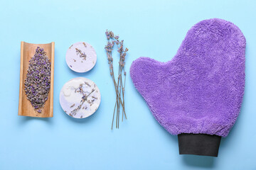 Soap bars, massage glove and lavender flowers on color background