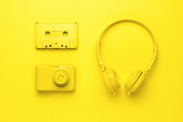 Yellow headphones, a camera and a tape recorder on a yellow background. Creative image.