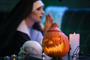 Halloween pumpkin and candles on table of praying nun