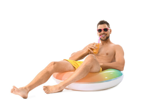 Young man with inflatable ring drinking juice on white background